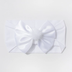 Détail du bandeau en nylon blanc pour bébé avec grand nœud en satin et pompon doux