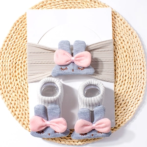 Detailed view of grey knitted baby headband and socks set with cute bunny ears and bows
