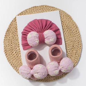 Détail du lot bonnet et chaussettes bébé avec gros nœud fleuri brodé en coton doux