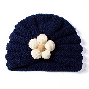 Dettaglio del cappello in maglia blu scuro per neonati con decorazione a fiori in velluto