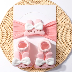 Detailed view of pink nylon baby headband and socks set with 3D bunny and bow on a mat