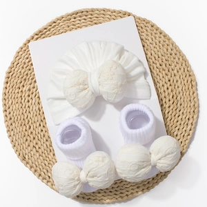 Détail de l'ensemble turban et chaussettes pour bébé blanc avec nœud en dentelle brodé