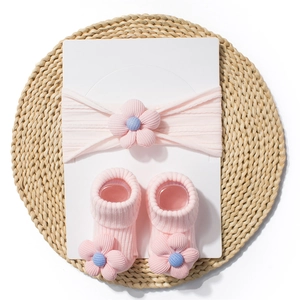 Close-up of pink baby headband and matching floral socks on a textured display card