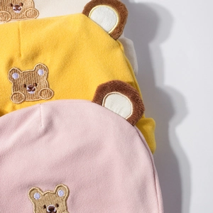Close-up of soft cotton baby hats featuring cute bear embroidery and plush 3D ears
