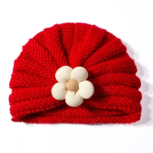 Dettaglio del berretto in maglia rossa per neonati con fiore 3D beige e trama a coste
