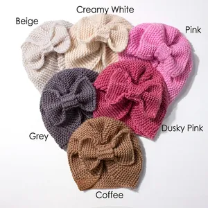 Close-up of knit baby turban hats with bow details in six assorted neutral colors