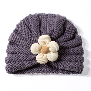 Dettaglio del cappello in maglia viola per neonati con grande fiore e coste