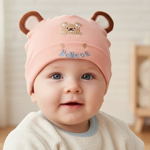 Close-up of pink cotton infant beanie featuring 3D bear ears and animal embroidery
