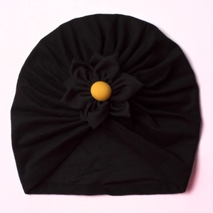 Close-up of baby turban hat featuring a black knit fabric and a 3D pleated flower detail