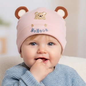 Close-up of pink cotton infant hat featuring 3D bear ears and detailed bear embroidery