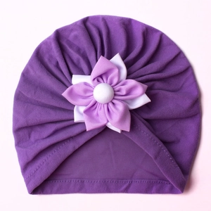 Detailed close-up of a purple baby turban hat with a decorative layered fabric flower