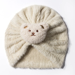 Detailed view of plush cream baby hat featuring a soft pink bear embroidery decoration