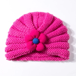 Dettaglio del cappello in maglia rosa per neonati con fiore 3D e trama morbida intrecciata