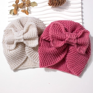 Chunky knit baby winter hats in beige and pink colors with large decorative bows
