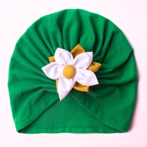 Detail of green baby turban hat featuring a 3D white and yellow fabric flower ornament