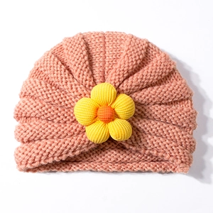 Dettaglio del cappello a turbante in maglia rosa per neonati con un fiore 3D giallo