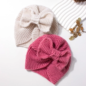 Knitted baby beanie with large bow accent in cream white and rose pink colors