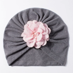Dettaglio del berretto in maglia grigia per neonato con un fiore rosa decorativo