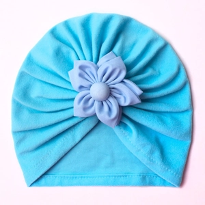 Close-up of blue baby turban hat featuring a 3D purple flower and soft knit fabric
