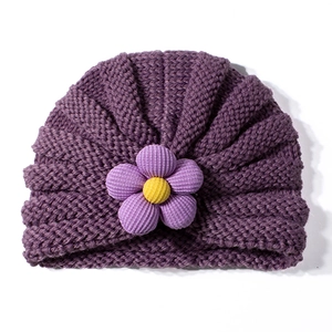 Dettaglio della texture del cappello in maglia viola scuro per neonati con fiore