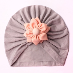 Detail of baby warm knit hat showing grey fabric and coral pink flower texture