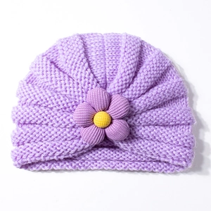 Dettaglio del turbante neonato in maglia viola con un fiore decorativo giallo e viola