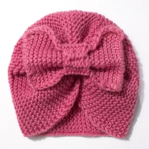 Close-up of deep pink chunky knit baby beanie featuring a large decorative bow