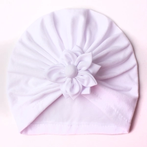 Detailed view of white baby turban hat with decorative flower and soft pleated fabric
