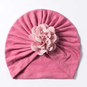 Dettaglio di un turbante rosa per neonati con fiore in tessuto a strati e morbido cotone