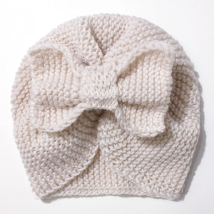 Detailed close-up of cream knit baby turban hat featuring a large soft bow decoration