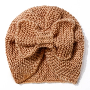 Detailed knit texture of ginger baby beanie featuring a large decorative bow