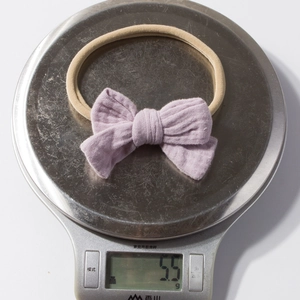 Detail shot of a purple cotton bow baby headband weighing only 5.5g on a digital scale