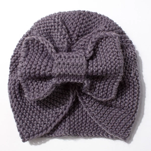Close-up of knit baby beanie with a large bow detail and textured crochet fabric