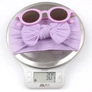 Lunettes soleil bébé roses et bandeau tricoté lavande sur une balance pesant 30,7g