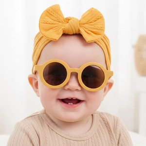 Détail de l'ensemble bandeau bébé à nœud tricoté et lunettes de soleil rondes jaune moutarde