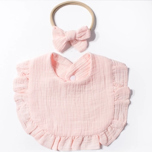 Dettaglio bavaglino neonato in mussola rosa con volant e fascia con fiocco coordinata