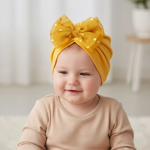 Détail du turban bébé jaune moutarde avec un grand nœud pailleté et un tissu extensible