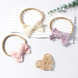 Set of three cotton waffle bow elastic headbands for infants in cream, lilac, and pink colors