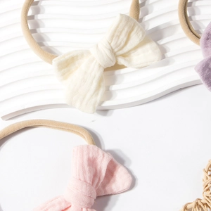 Detail showing elastic nylon baby headbands with textured cotton bow in soft pastel colors
