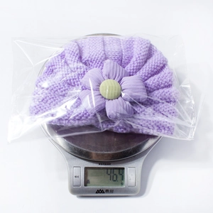 Detailed weight display of purple striped baby knit hat with flower accent in packaging