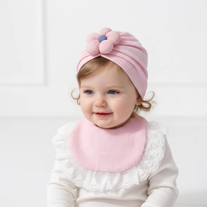 Set berretto rosa con fiore e bavaglino in pizzo per neonati indossato da un modello