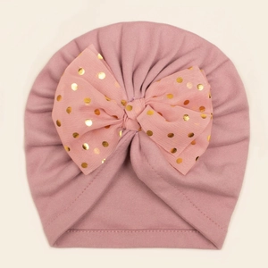 Détail du bonnet turban pour bébé rose avec un grand nœud en mousseline à pois dorés