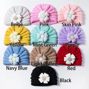 Flat lay of baby turban hats in ten different colors with knit flower details