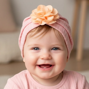 Détail du bonnet turban pour bébé en tricot rose avec une grande fleur en tissu orange