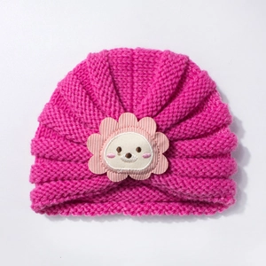 Détail d'un bonnet en tricot rose vif pour bébé avec un écusson d'animal mignon brodé
