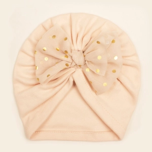 Détail d'un bonnet turban pour bébé avec grand nœud en résille pêche et pois dorés