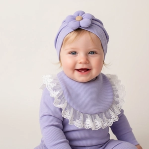 Dettaglio del cappello in maglia viola con fiore e body a costine con pizzo