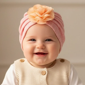 Détail du turban rose côtelé pour bébé avec une fleur décorative en organza sur le dessus