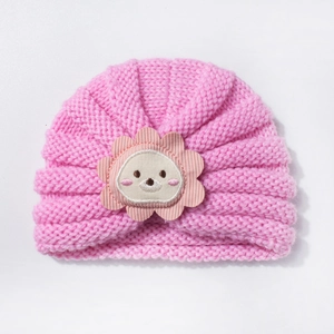 Détail du bonnet en tricot pour bébé avec texture laine rose et écusson animal mignon