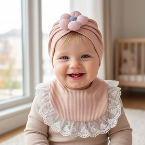 Dettaglio del turbante rosa per neonati con fiore e bavaglino in pizzo in set regalo